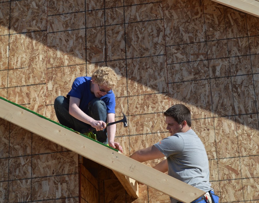 Josh Webber, left, is ready to hammer in a nail on a board being held by Brayden Spore on one of the roof lines. The two Wawasee building trades students are helping to build a home in Elkhart County.
