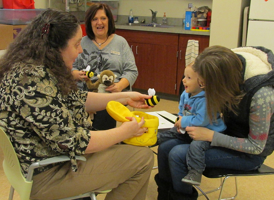 Gideon Rensberger has fun with Mrs. Pam during Lapsit, a program for infants ages birth to 24 months. Holding Gideon is his mother Jamie Rensberger.