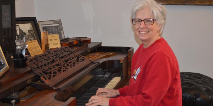 Kosciusko County Historical Society Museum Director Sally Hogan shows off one of the pianos in the Old Jail Museum. (Photo by Amanda McFarland)