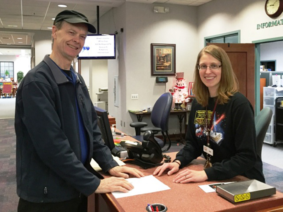 Sign up for the Adult & Teen Winter Reading Program. Read (or listen to audiobooks), count pages, and pick a prize! Pictured is David Beyer and Anna Jackson, Information Services. 