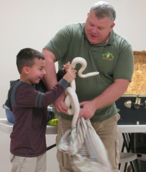 Animal handler Mark Kohlhorst (right) introduces Snowball the Snake to Jac Cook at Mark’s Ark Live Animal Show held recently at the North Webster Library.
