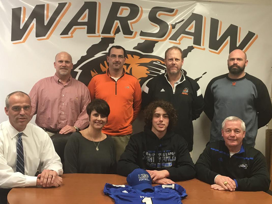 Warsaw football star Brock Riley signed on to continue his gridiron career with the University of St. Francis. Seated with Brock are PICTURED: Front Row (L-R): Tony Riley, Ingrid Riley, Brock Riley, Doug Coate (USF Backs Coach); Back Row (L-R): Dave Anson (WCHS Athletic Director), Matt Thacker (WCHS Offensive Coordinator), Phil Jensen (WCHS Head Coach), Kris Hueber (WCHS Defensive Coordinator). (Photo provided)