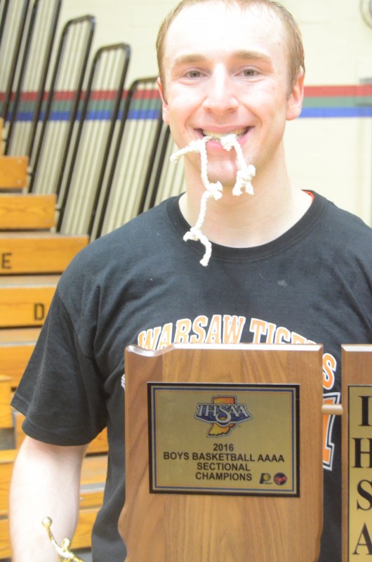 Warsaw guard Evan Schmidt enjoys a lighter moment with the sectional championship trophy.