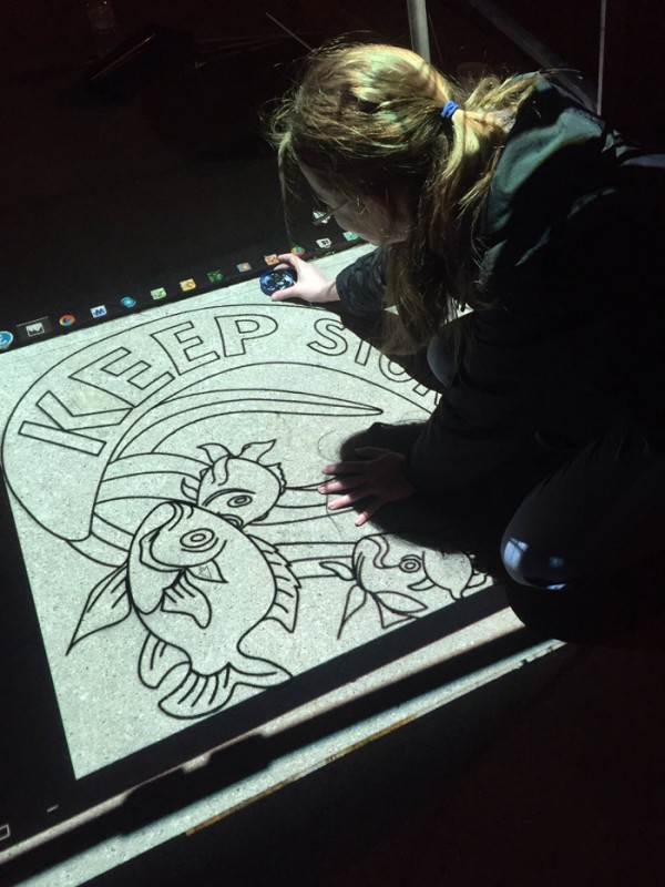 Grace College students paint storm drain art outside of the Kosciusko County Courthouse building. (Photo provided)