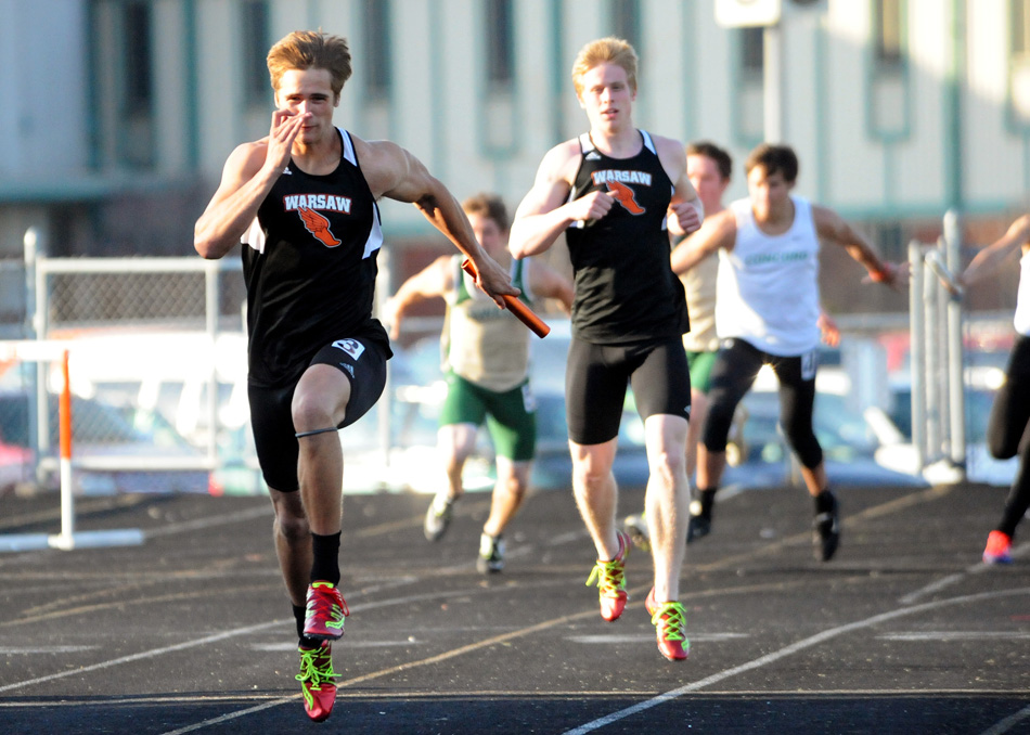 Warsaw's Brandon Reinholt sprints down the final stretch as Ross Armey looks on as the Tiger 4x100 relay cruised to a win Thursday night. (Photos by Mike Deak)