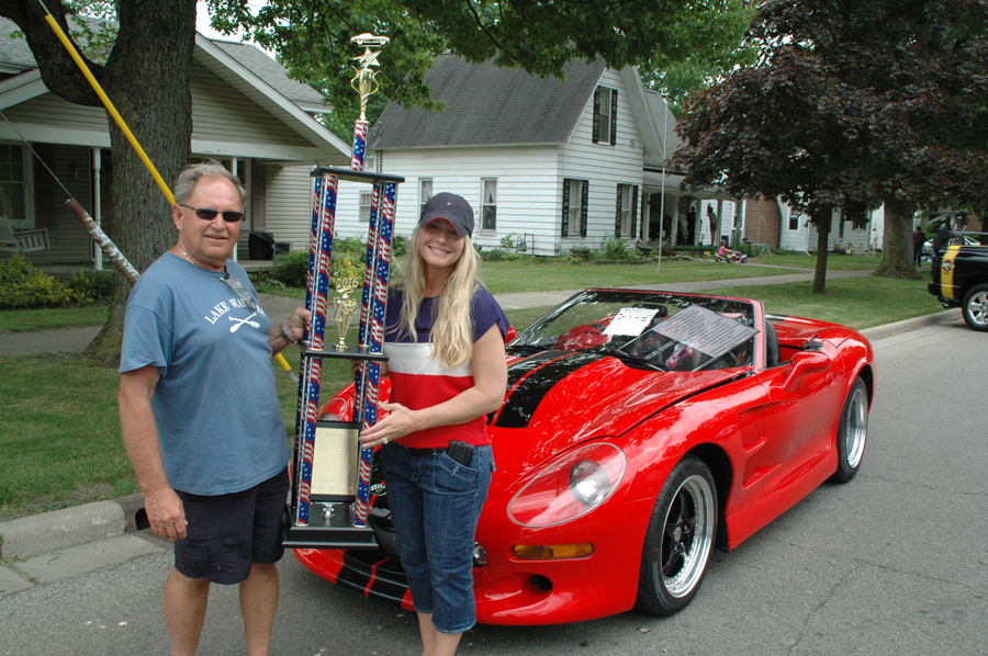 Mike Tiltges, left, won the Milford Fest Car/Tractor/Motorcycle Best In Show trophy, which was presented by Milford Party Pack owner, Nicole Dippon, who will continue sponsoring the trophy, following in the tradition of Don Trammel, who did so for 15 years.