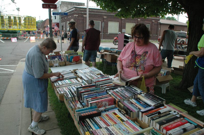 Milford's Susan Berger, right, peruses the stacks at the Friends of Milford Library book sale.