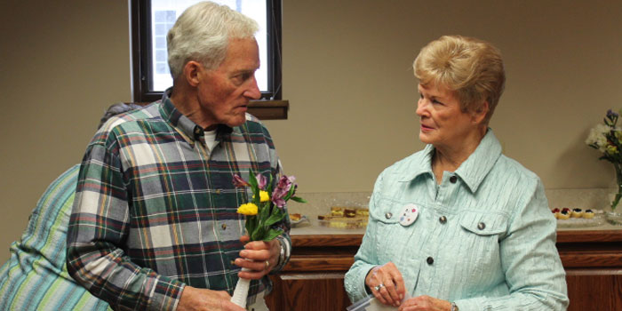 Volunteers at the Syracuse Library were honored at a Friend to Friend dessert held May 5. Pictured from left are Don Impey and Jan Rose. Impey is shown with his flowers of appreciation while he discusses the volume of used books that are recycled through the Syracuse Library. Rose is a new member with the Syracuse Friends. (Photo provided)