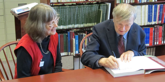 An autographed copy of "Autocourse Official History of the Indianapolis 500" by Donald Davidson & Rick Shaffer, was donated to the library in honor of the Indy 500 Centennial. Library Director, Ann Zydek watches as Donald Davidson signs the book.