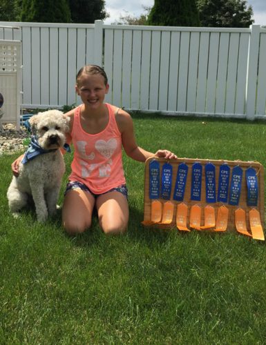 Baxter poses with his human buddy and a collection of ribbons they have won together.