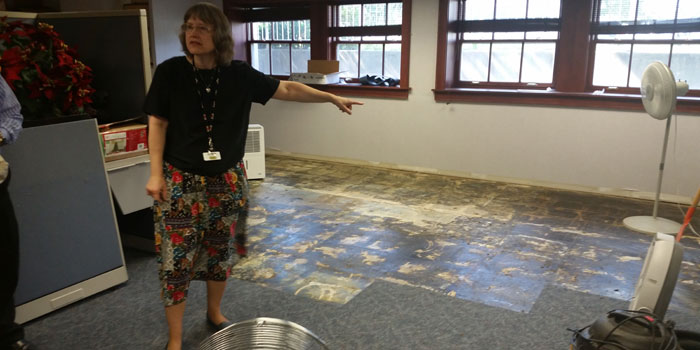 WCPL Director shows the board some of the floor damage done during June's heavy rains. (Photo by Amanda McFarland)