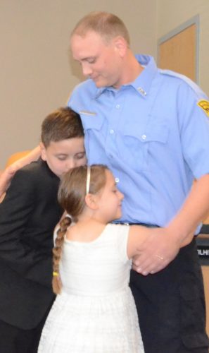 Wyatt and Laila Stamper give their father, Trent, a hug after he was officially sworn in as a Warsaw-Wayne Township Fireman.