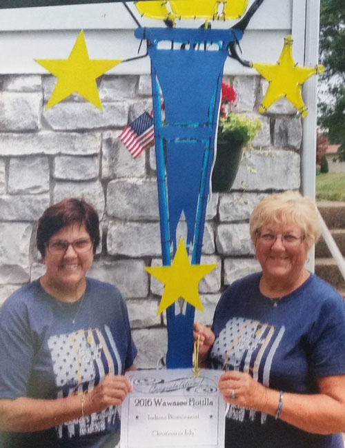 Cathy Baker, left, and Carolyn Lemberg pose in front of a torch after being named Bicentennial Torchbearers.
