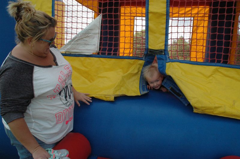 Tara Brandon, left, plays peek-a-boo with niece, Kambry Myers, at the North Webster Fall Festival bouncy castle