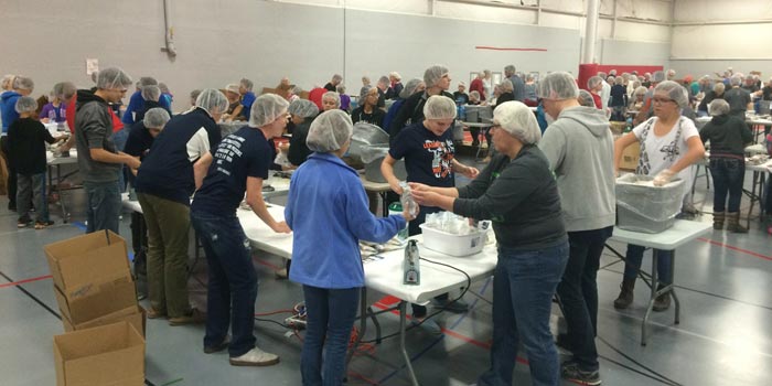 Volunteers help pack food for starving children.