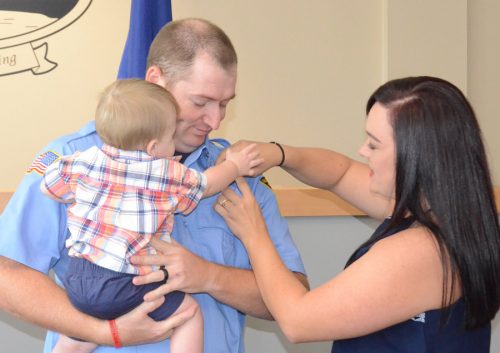 Zander Waters gives his mother, Elizabeth, a helping hand, pinning the firefighter badge on his father's shirt. Miles Waters was sworn in as a new full time officer of the department.