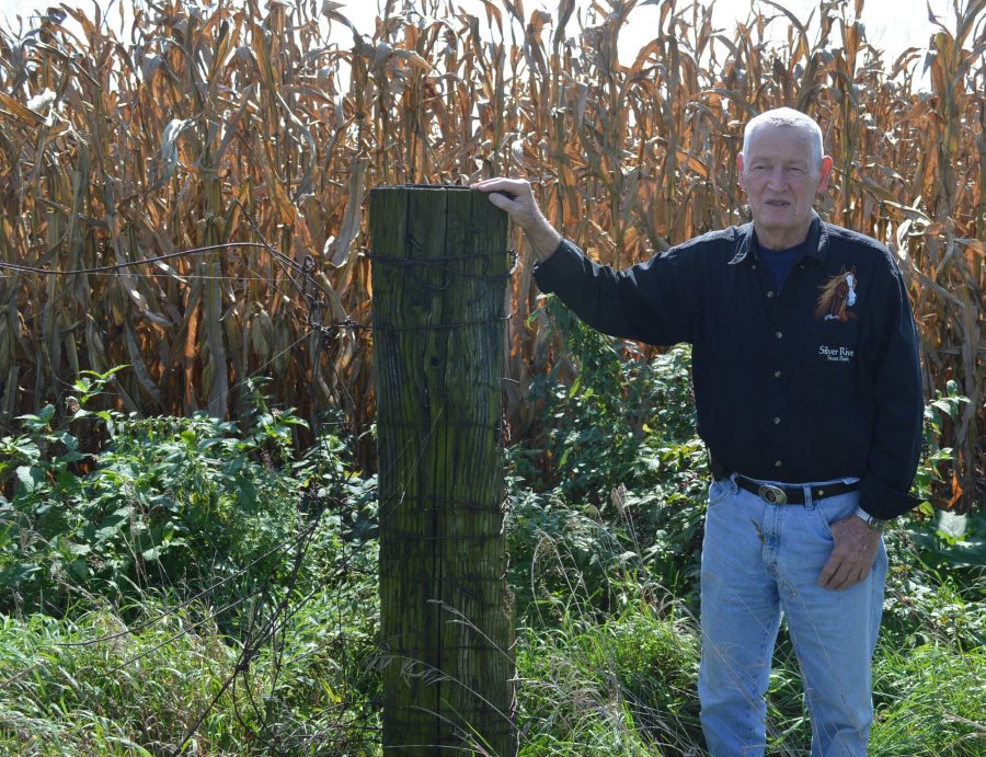 Eddie Creighton stands next to an old railroad tie used in a fence line many years ago on the former Myers farm in Harrison Township. Behind him is corn waiting to be harvested.