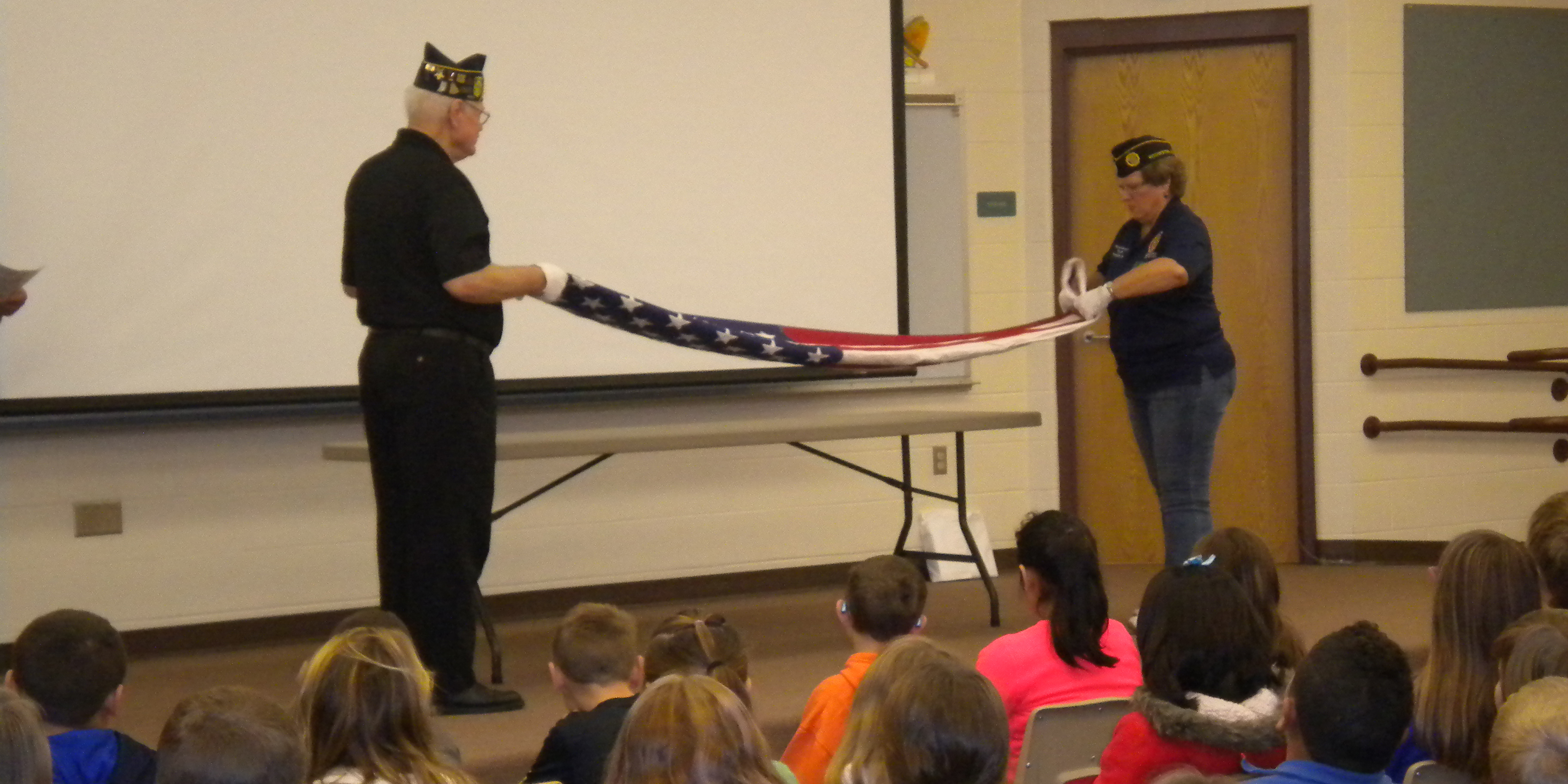 Jon Lybarger, left, and Monica Clennon teaching fourth grade students at Mentone Elementary the proper way to fold an American flag.