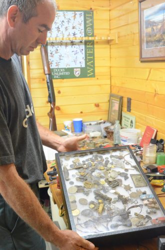 Todd McCulloch looks at the various coins, buckles, knives, necklaces and other items he has found in the waters of Lake Wawasee.