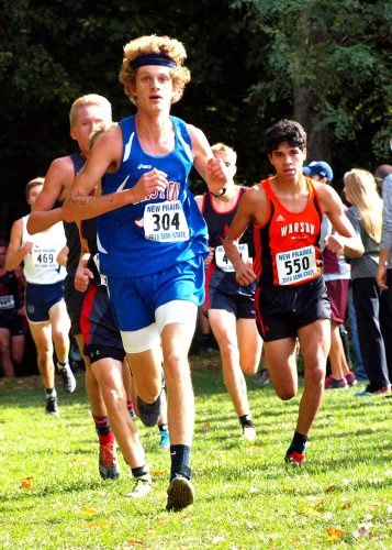 Warsaw sophomore Zeb Hernandez (550, right) chases eventual champ Mitchell Rans of Caston (304) out of the woods near the 3,000-meter mark during the boys cross country semistate Saturday at New Prairie. Rans and Hernandez finished 1-2. (Photos by Tim Creason)