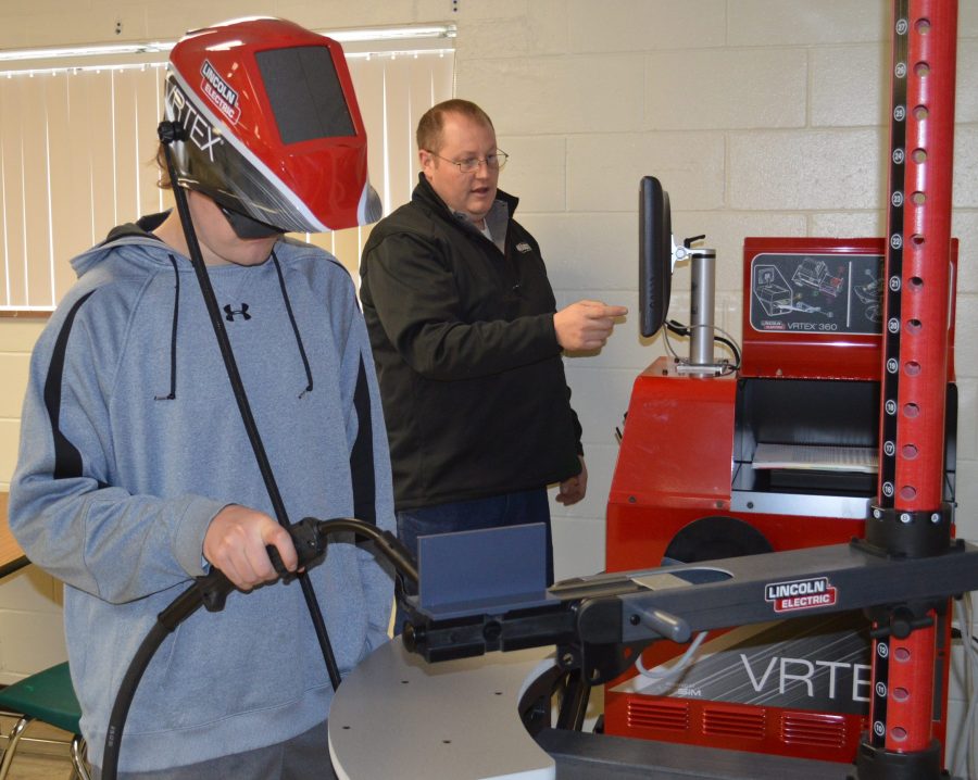 Dominic Richardson, Wawasee High School student, uses the virtual welder while in the background instructor Jesse Kimmel monitors the computer screen.